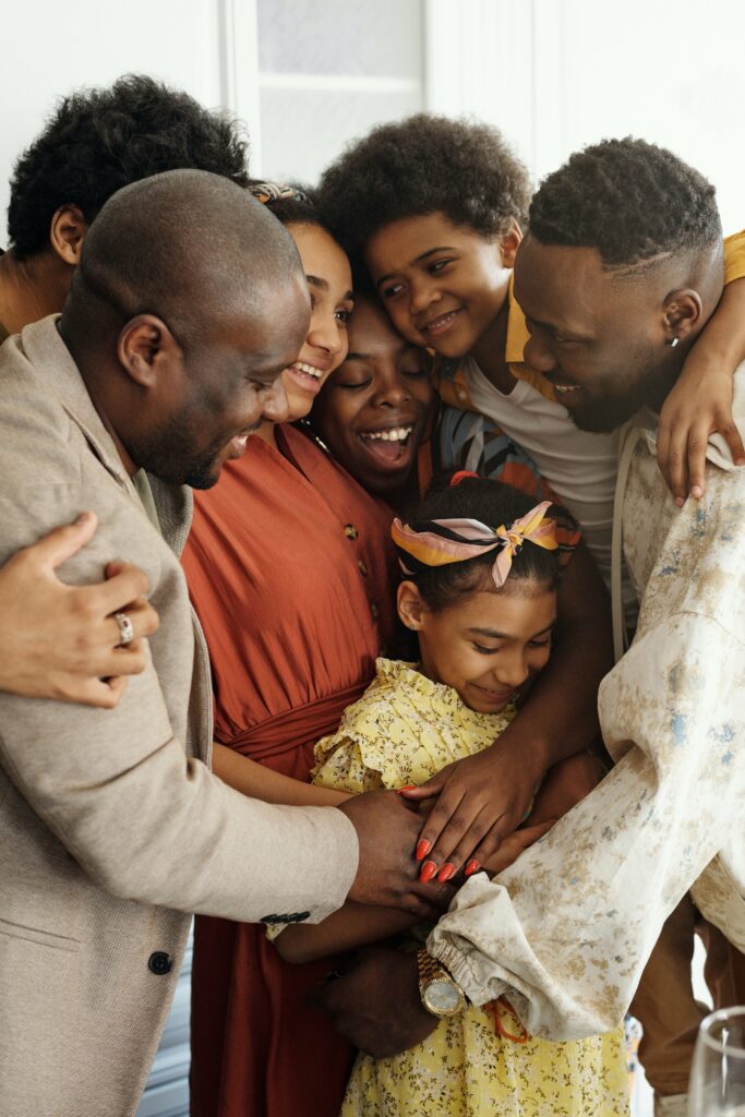 A family gathers around a young girl wearing a yellow dress and an orange and blue hair tie