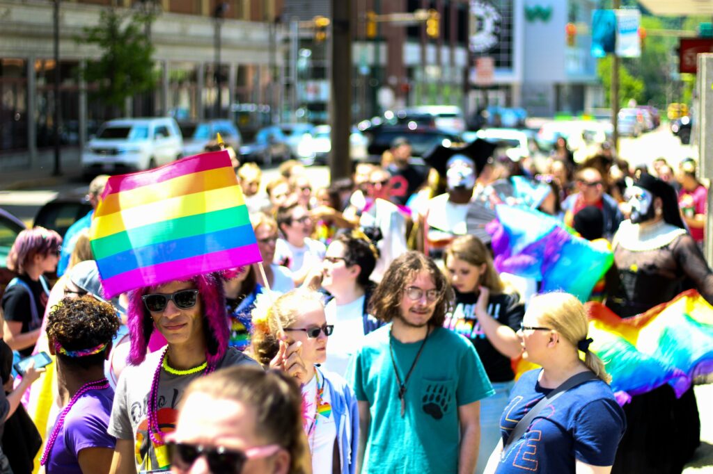 A group of people wave rainbow flags and banners at a pride parade